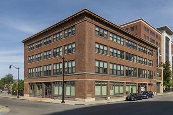 A large red brick building with a black car parked in front.